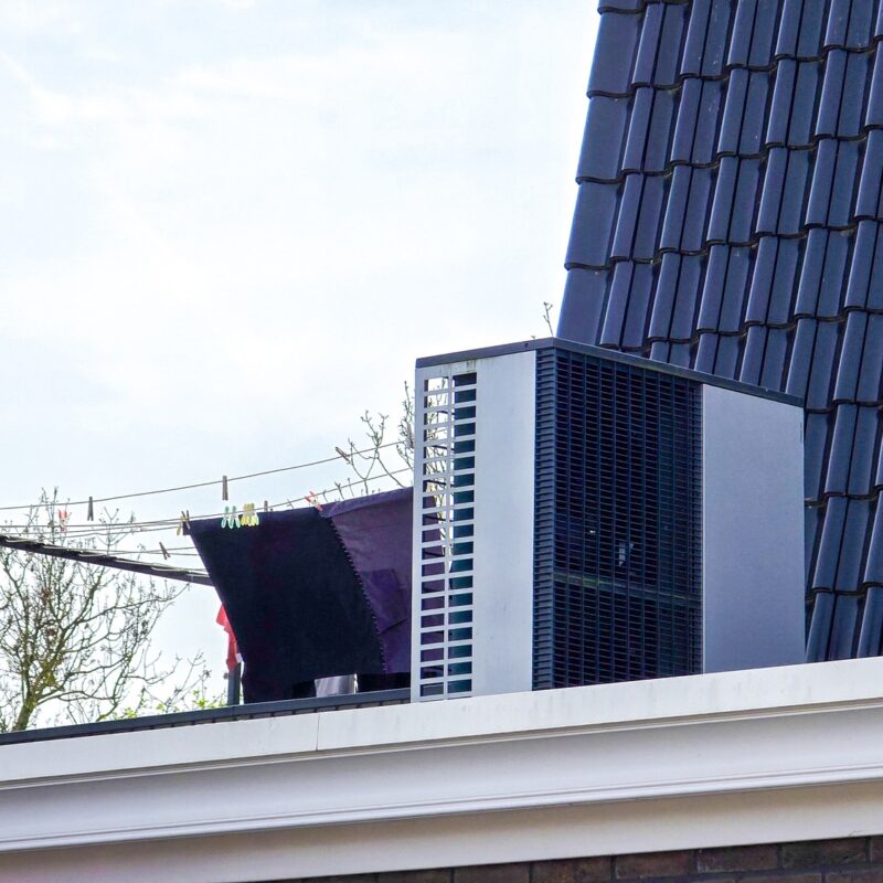 air source heat pump unit installed outdoors at a modern home with solar panels in the Netherlands