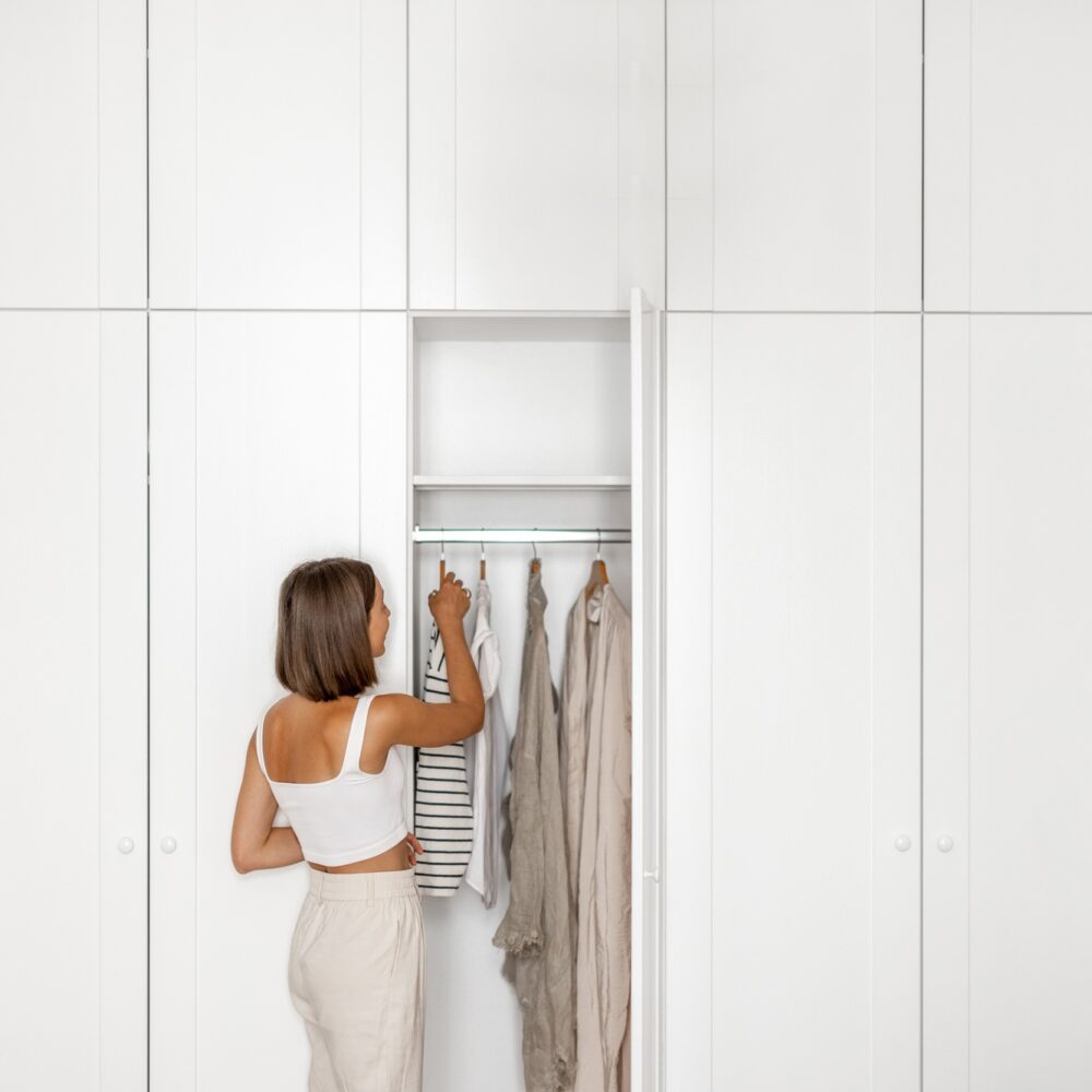 Young woman chooses what to wear near the closet