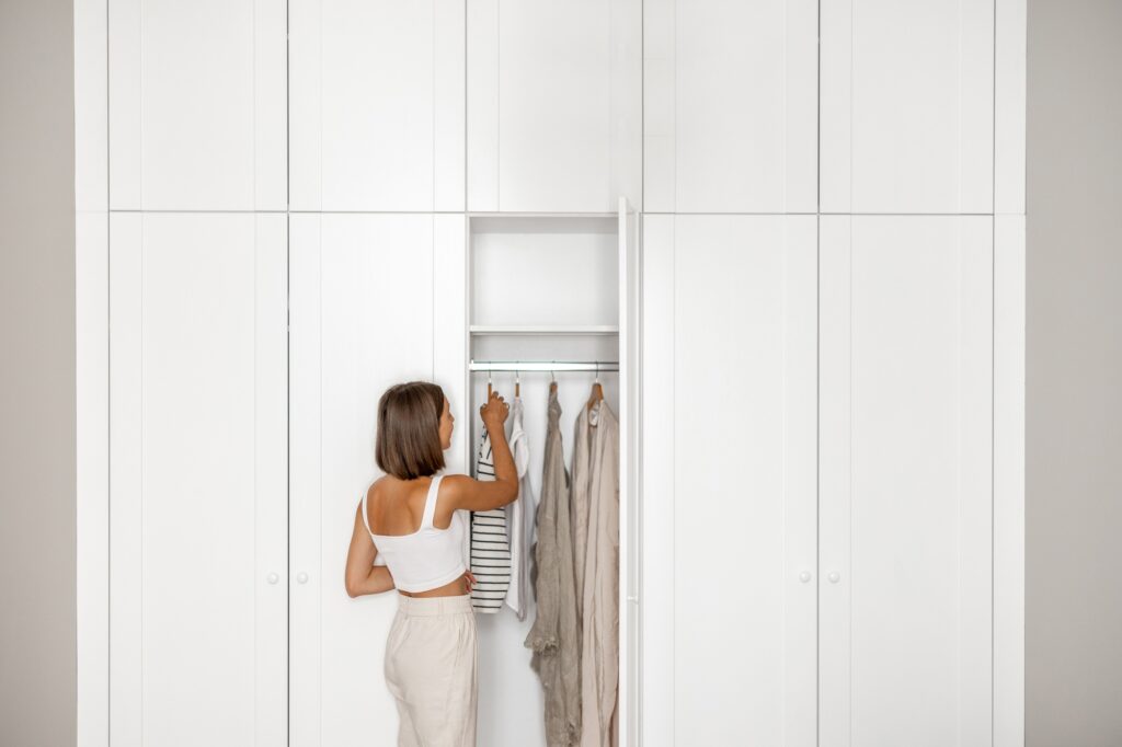 Young woman chooses what to wear near the closet